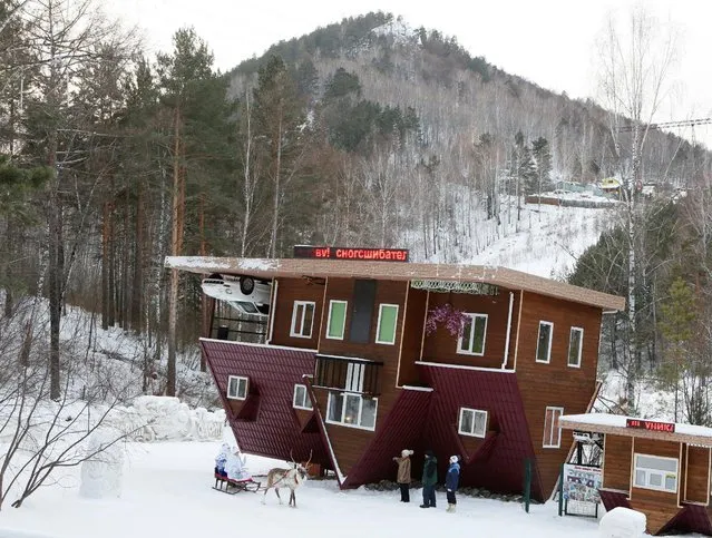 Employees dressed as Ded Moroz, the Russian equivalent of Santa Claus, and his granddaughter Snegurochka (Snow Maiden), sit on a sledge harnessed with a reindeer while waiting for visitors outside an upside down house, constructed as an attraction for local residents and tourists and located at the Royev Ruchey Park of Flora and Fauna in the suburbs of Krasnoyarsk, Russia, December 7, 2016. (Photo by Ilya Naymushin/Reuters)