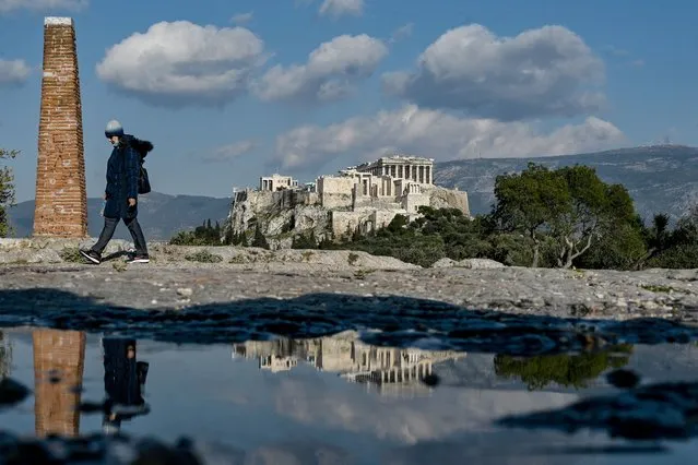 A woman walks on a hill overlooking the ancient Acropolis in Athens on April 1, 2021, a day after Greece said it would reopen most shops and relax leisure restrictions despite persistently high Covid-19 deaths and infections that have put its health system under major strain. (Photo by Louisa Gouliamaki/AFP Photo)