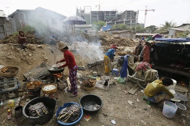 Women grill fishes for sale at a slum area near railway tracks in Phnom Penh, Cambodia January 13, 2016. (Photo by Samrang Pring/Reuters)