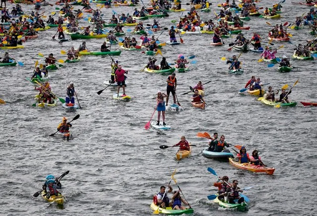 Participants take part in the annual TraverSeine event with their canoe, kayak and stand up paddles, along the Seine river in Paris, on September 17, 2023. (Photo by Julien de Rosa/AFP Photo)