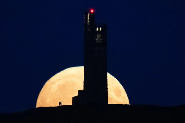 The full moon, called the Super Blue Moon, rises behind Victoria Tower on Castle Hill, above Huddersfield, on August 30, 2023. (Photo by Oli Scarff/AFP Photo)