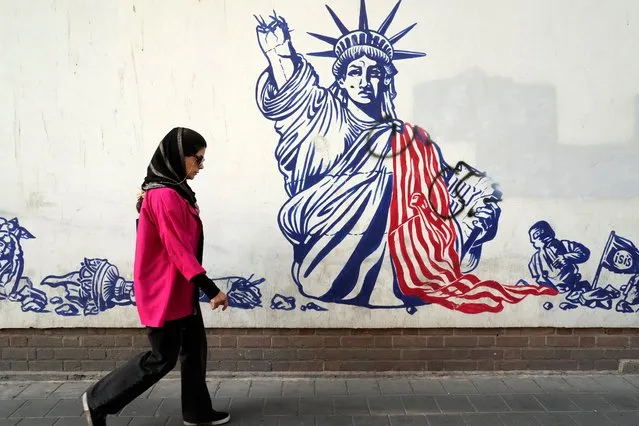 A woman walks past an anti-American mural on the wall of the former U.S Embassy in Tehran, Iran, Saturday, August 19, 2023. Seventy years after a CIA-orchestrated coup toppled Iran’s Prime Minister Mohammad Mossadegh, its legacy remains contentious and complicated for the Islamic Republic as tensions stay high with the United States. (Photo by Vahid Salemi/AP Photo)