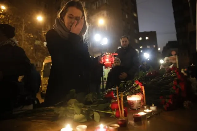 A woman lights a candle at the well-known military choir's building in Moscow, Russia, Sunday, December 25, 2016, after a plane carrying 92 people, including 64 members of the Alexandrov Ensemble, crashed into the Black Sea minutes after taking off from the resort city of Sochi. The Russian plane was headed for an air base in Syria, Russia's Defense Ministry said. (Photo by Pavel Golovkin/AP Photo)