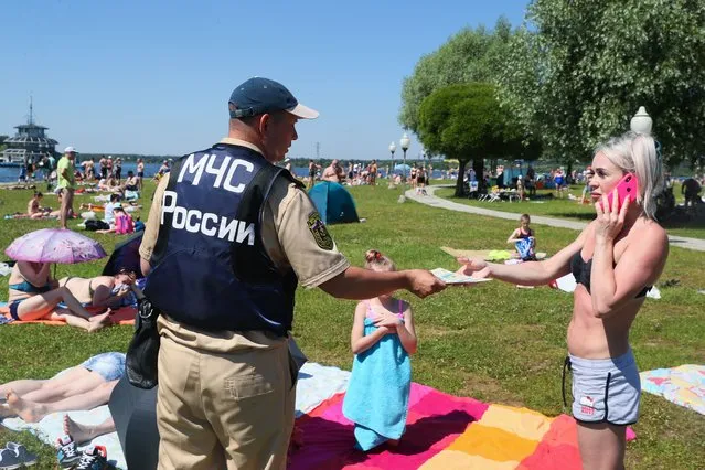 The Ministry of Emergency Situations distributes leaflets with safety guidelines to people on Pirogovo beach on the Klyazma reservoir near Moscow on June 24, 2021. (Photo by Alexander Shcherbak/TASS)
