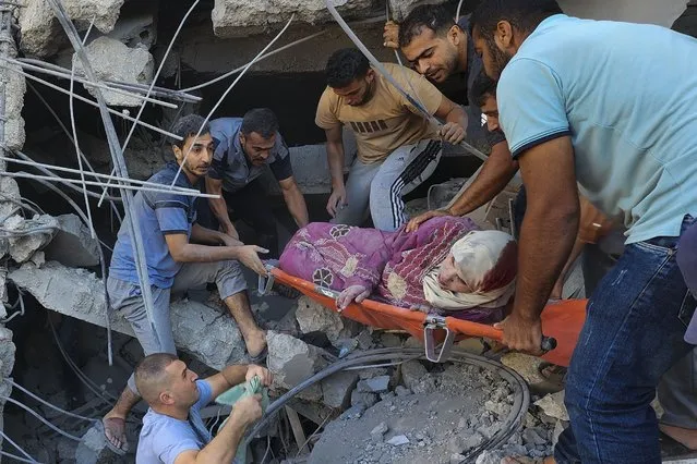 Palestinians rescue a woman after an Israeli airstrike on buildings of the Abu Asad family in Deir el-Balah, southern Gaza Strip, Saturday, October 21, 2023. (Photo by Hassan Eslaiah/AP Photo)