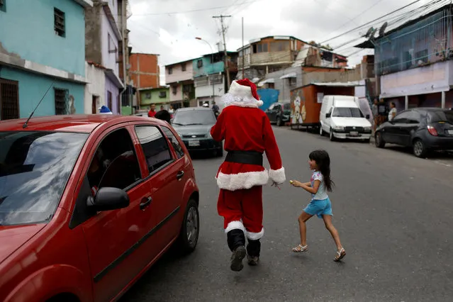 Richard Gamboa walks in a street of the slum Cota 905 during the “Santa en las calles” (Santa in the streets) event donating toys, food, and clothes in Caracas, Venezuela on December 1, 2018. (Photo by Marco Bello/Reuters)