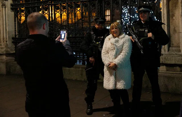 A woman poses for a photograph with armed police officers patrolling ahead of New Year's celebrations in London, Britain December 31, 2016. (Photo by Neil Hall/Reuters)