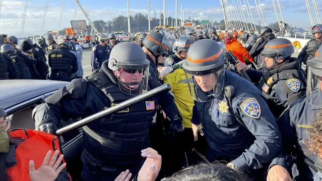 Police officers clear protesters blocking the San Francisco-Oakland Bay Bridge while demonstrating against the APEC summit Thursday, November 16, 2023, in San Francisco. (Photo by Noah Berger/AP Photo)