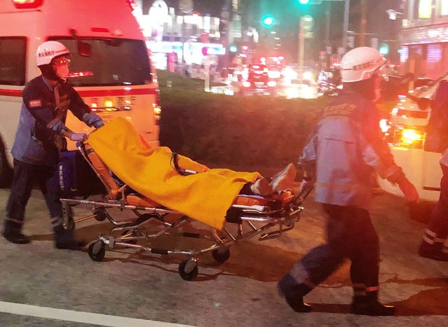Rescuers carry an injured passenger on  stretcher at Soshigaya Okura Station after stabbing on a commuter train, in Tokyo Friday night, August 6, 2021. A man with a knife attacked 10 passengers on a commuter train in Tokyo on Friday and was arrested by police after fleeing, fire department officials and news reports said. (Photo by Kyodo News via AP Photo)