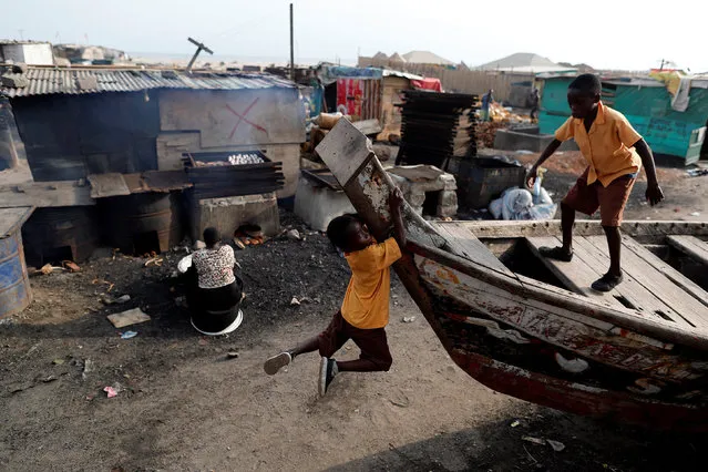Boys play as a woman prepares smoked fish in Jamestown in Accra, Ghana on November 28, 2018. (Photo by Zohra Bensemra/Reuters)