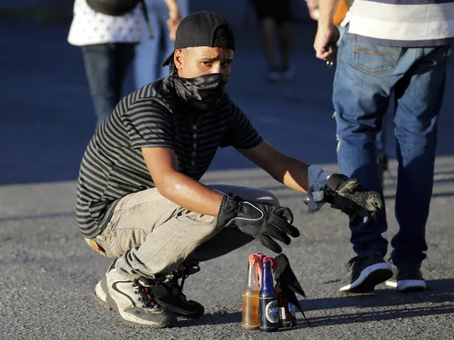 An anti-government protester readies gasoline bombs during clashes against the Venezuelan Bolivarian National Guard, after a rally demanding the resignation of President Nicolas Maduro in Caracas, Venezuela, Wednesday, January 23, 2019. The head of Venezuela's opposition-run congress declared himself interim president at the rally, until new elections can be called. (Photo by Fernando Llano/AP Photo)