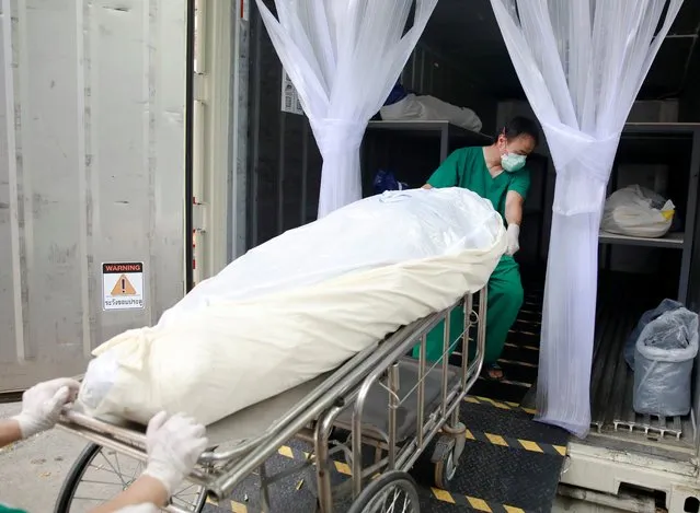 Health care workers move a dead body to a container after a hospital morgue overwhelmed by COVID-19 deaths begun to store bodies in refrigerated containers, as the country struggles to deal with its biggest outbreak to date, in Pathum Thani, Thailand on July 31, 2021. (Photo by Soe Zeya Tun/Reuters)