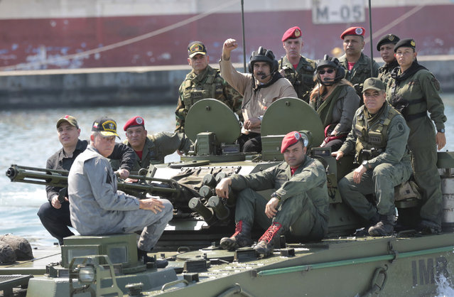In this photo released to the media by Miraflores presidential palace press office, Venezuelan President Nicolas Maduro raises his fist from an amphibious tank as he poses for photos alongside first lady Cilia Flores and Defense Minister Vladimir Padrino Lopez, center right, at the Naval base in Puerto Cabello, Venezuela, Sunday, January 27, 2019. Opposition lawmaker Juan Guaido has declared himself Venezuela's legitimate leader, as embattled socialist Maduro holds the reins of power. (Photo by Marcelo Garcia/Miraflores presidential palace press office via AP Photo)