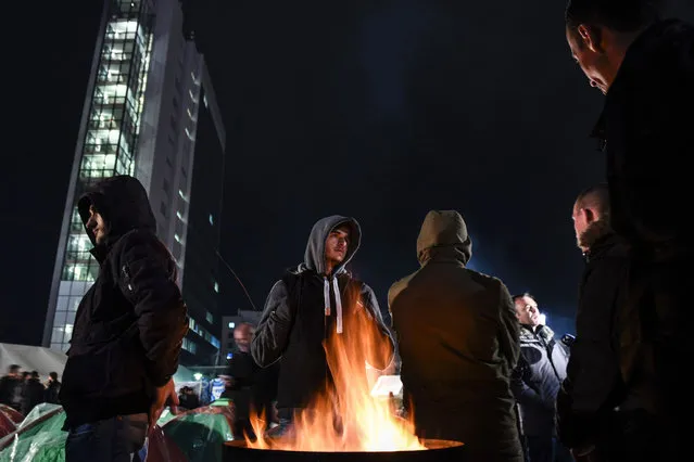 Opposition party supporters keep warm by a fire as they gather in front of Kosovo's government building in Pristina on February 24, 2016, to demand the resignation of the government, during the latest eruption in a long-running protest against agreements made with Serbia. (Photo by Armend Nimani/AFP Photo)