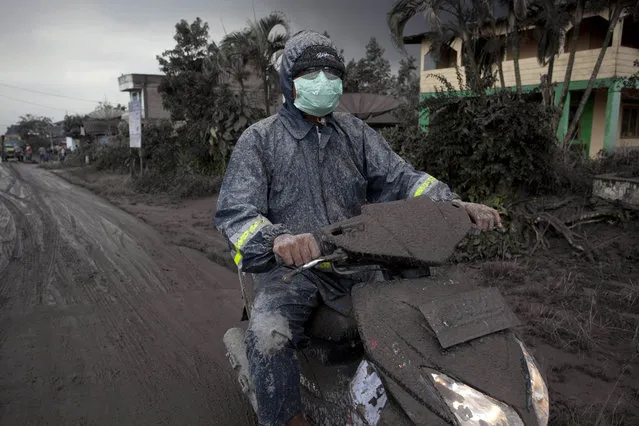 An ash covered a motorcyclist as drives on a road covered with ash following a further eruption of the Mount Sinabung on January 4, 2014 in Karo District, North Sumatra, Indonesia. (Photo by Ulet Ifansasti/Getty Images)