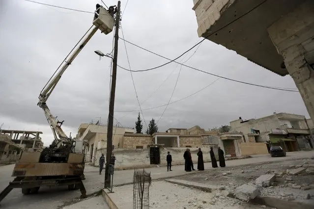 Residents inspect the damage as a man fixes damaged electricity cables at a site hit by shelling in the rebel-controlled area of Khan Sheikhoun, in Idlib province, Syria March 4, 2016. (Photo by Khalil Ashawi/Reuters)