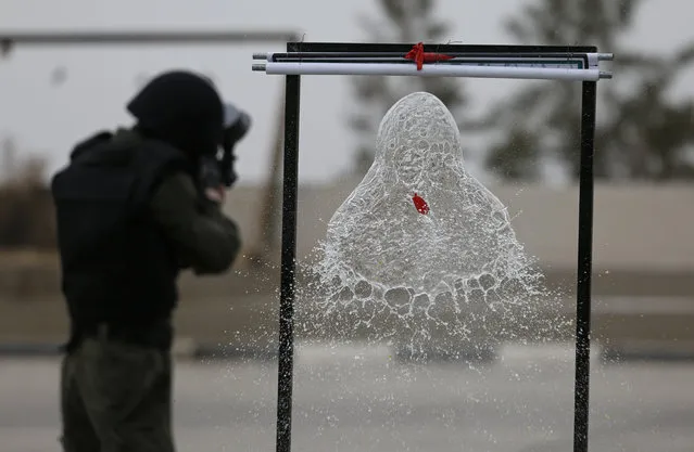 Palestinians shoot a water balloon with a paint gun during a training session at a youth camp with Palestinian security forces, in the West Bank city of Jericho, Wednesday, January 25, 2017. The participants wear military uniforms and spend 3 days in the military camp. (Photo by Majdi Mohammed/AP Photo)