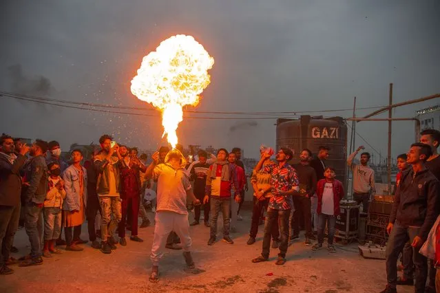 A Bangladeshi youth spits fire to entertain onlookers during the Poush Sankranti celebration in Old Dhaka, Bangladesh, 14 January 2022. The annual festival is also known as Makar Sankranti and marks the end of the Bengali mouth of Poush. The government announced an 11- points new guideline and further restrictions which came into effect on 13 January to fight the spreading of the Omicron variant of SARS-CoV-2 virus that causes the COVID-19 disease. (Photo by Monirul Alam/EPA)
