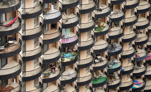 A man sits on his balcony amid a sea of balconies at an apartment building in Arlington, Virginia on October 13, 2021. (Photo by Kevin Lamarque/Reuters)