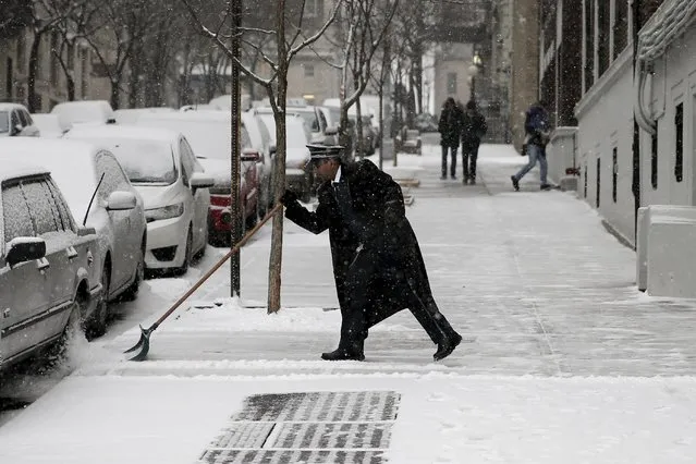 A doorman shovels snow near Riverside Drive in the Manhattan borough of New York City, February 15, 2016. (Photo by Mike Segar/Reuters)