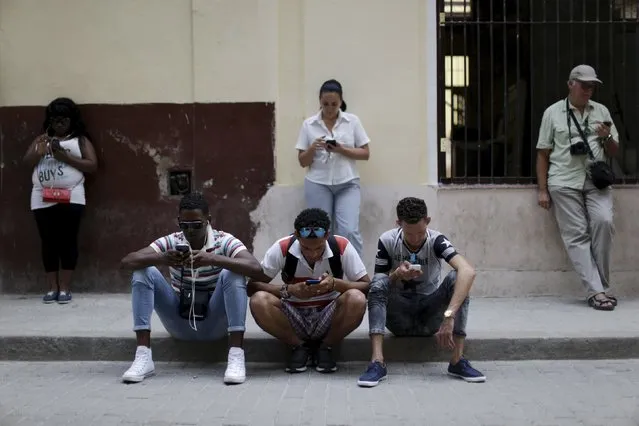 People sit and stand near a Wi-Fi hotspot in Havana, March 17, 2016. (Photo by Ueslei Marcelino/Reuters)