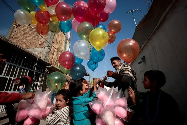 Children gather around a man selling balloons in Khwaja Bughra street in Kabul, Afghanistan, November 7, 2021. (Photo by Zohra Bensemra/Reuters)