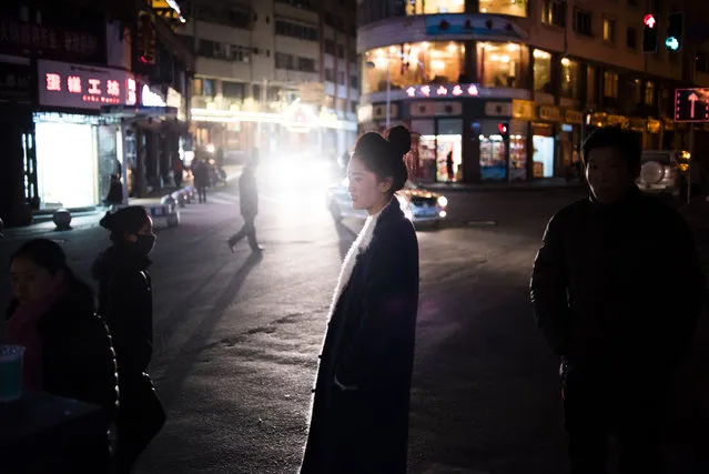 In this photo taken on December 6, 2015, a woman walks on a street at Kangding in the Ganzi Tibetan Autonomous Prefecture, southwestern China's Sichuan Province. Chinese authorities say urbanisation in Tibet an areas and elsewhere will increase industrialisation and economic development, offering former nomads higher living standards and better protecting the environment. But critics say the drive has a one-size-fits-all approach and many former pastoralists have not prospered, despite its promises. (Photo by Fred Dufour/AFP Photo)