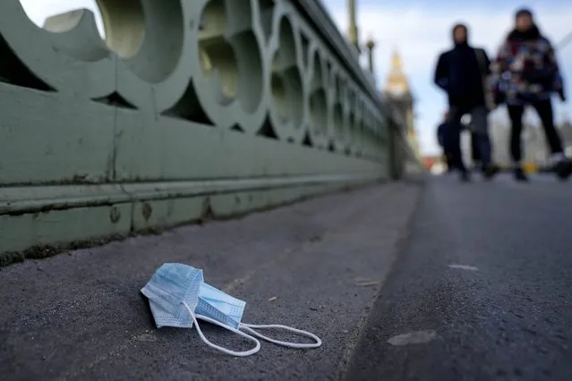 A used face mask on Westminster Bridge in London, Thursday, December 9, 2021. British Prime Minister Boris Johnson has announced tighter restrictions to stem the spread of the omicron variant. He is again urging people to work from home and mandating COVID-19 passes to get into nightclubs and large events. (Photo by Frank Augstein/AP Photo)