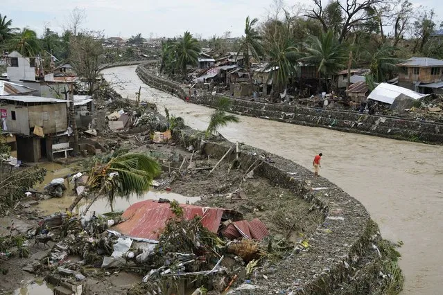 A man stands beside damaged homes along a swollen river due to Typhoon Rai in Talisay, Cebu province, central Philippines on Friday, December 17, 2021. (Photo by Jay Labra/AP Photo)