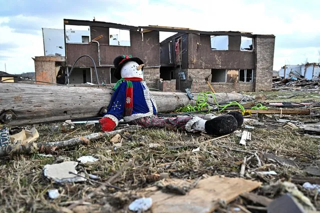A Frosty the Snowman doll sits against a fallen utility pole on a Christmas morning in a heavily damaged neighborhood, after tornadoes ripped through several U.S. states, in Dawson Springs, Kentucky, U.S., December 25, 2021. (Photo by Jon Cherry/Reuters)