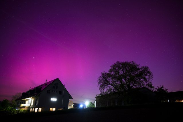 The Northern lights (aurora borealis) glow in the night sky above the village of Daillens, Switzerland, 11 May 2024. The National Oceanic and Atmospheric Administration (NOAA) of America has warned that the strongest geomagnetic storm for 20 years is set to hit Earth, making the Aurora Borealis, or Northern Lights, visible at much lower geomagnetic latitudes than usual. (Photo by Laurent Gillieron/EPA)
