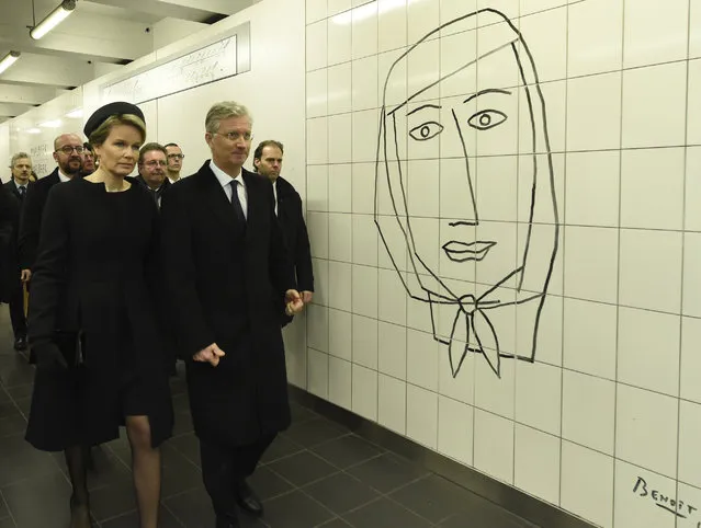 Queen Mathilde of Belgium (L) and King Philippe of Belgium (R) pass by a Benoit Van Innis artwork as they arrive for a minute of silence at 09:11 in the Maelbeek - Maalbeek subway station as tribute to the victims of last year terrorist attacks in Brussels, on March 22, 2017. Belgium marks the first anniversary of the Islamic State bombings in Brussels, one at the airport and the other in the metro, in which 32 people were killed and more than 320 wounded with ceremonies showing that the heart of Europe stands defiant. (Photo by Didier Lebrun/AFP Photo)