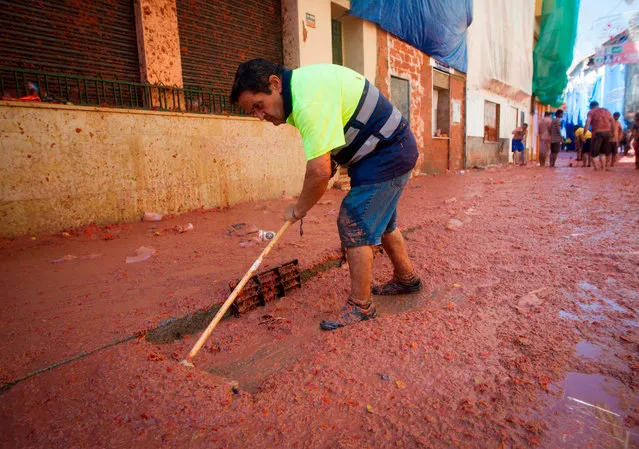 A worker cleans a street covered in tomato pulp during the annual “Tomatina” festival in the eastern town of Bunol, on August 28, 2019. (Photo by Jaime Reina/AFP Photo)