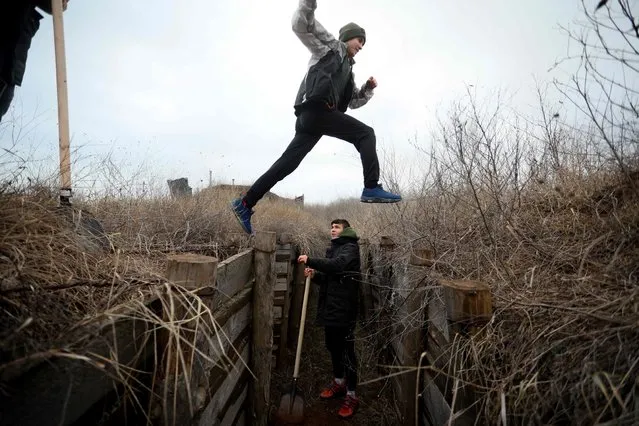 Ukrainian teenagers dig trenches for soldiers serving on their country's eastern front and facing off with Russian-backed separatists, near the eastern Ukraine village of Chervone, Mariupol region, on February 11, 2022. (Photo by Aleksey Filippov/AFP Photo)