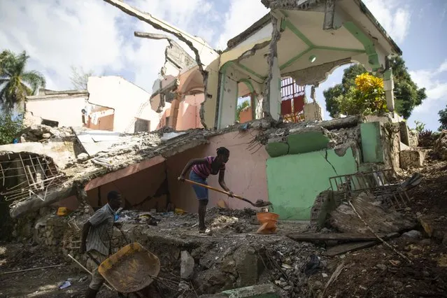 Luben Michel is helped by his wife Jeudi Remie to clear their house which was destroyed by the 7.2 magnitude earthquake six months ago in Marceline, Les Cayes, Haiti, Thursday, February 17, 2022. (Photo by Joseph Odelyn/AP Photo)