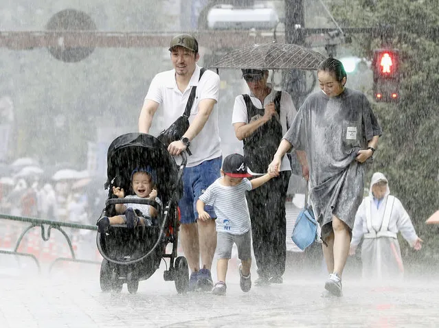 In this September 8, 2019, photo, people walk through heavy rain caused by typhoon in Tokyo. (Photo by Kyodo News via AP Photo)