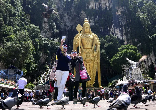 ourists take selfie with the Lord Murugan statue at Batu Caves in Kuala Lumpur, Malaysia on Friday, April 21, 2017. (Photo by Daniel Chan/AP Photo)