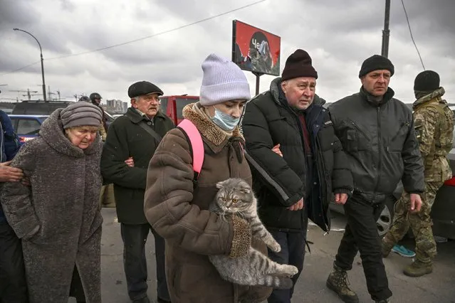 Ukrainian people walk as they evacuate the city of Irpin, northwest of Kyiv, on March 13, 2022. Russian forces advance ever closer to the capital from the north, west and northeast. Russian strikes also destroy an airport in the town of Vasylkiv, south of Kyiv. A US journalist was shot dead and another wounded in Irpin, a frontline northwest suburb of Kyiv, medics and witnesses told AFP. (Photo by Aris Messinis/AFP Photo)