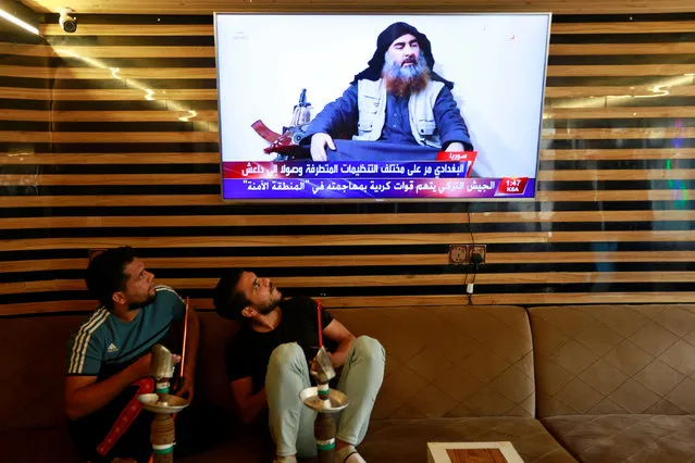 Iraqi youth watch the news of Islamic State leader Abu Bakr al-Baghdadi death, in Najaf, Iraq on October 27, 2019. (Photo by Alaa al-Marjani/Reuters)