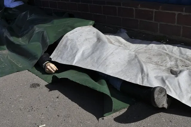 A body lies covered after Russian shelling at the railway station in Kramatorsk, Ukraine, Friday, April 8, 2022. (Photo by Andriy Andriyenko/AP Photo)