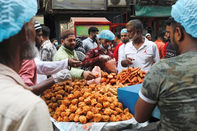 People purchase food for iftar meal from the Chawkbazar makeshift market during the first day of the holy month of Ramadan in Dhaka, Bangladesh on April 3, 2022. (Photo by Mohammad Ponir Hossain/Reuters)