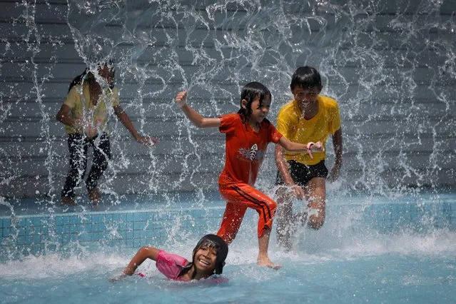 Children play in the pool in front of Malaysia's landmark Petronas Twin Towers in Kuala Lumpur, Malaysia, Thursday, June 12, 2014. (Photo by Vincent Thian/AP Photo)