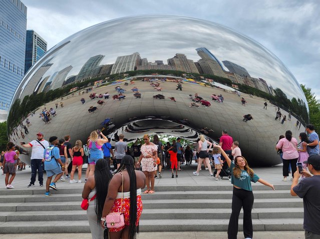 Visitors pose for photographs in front of the Cloud Gate sculpture as it reflects the skyline in Chicago, Illinois, on August 1, 2024. Chicago will host the 2024 Democratic National Convention at the nearby United Center from August 19 through August 22. (Photo by Tannen Maury/AFP Photo)