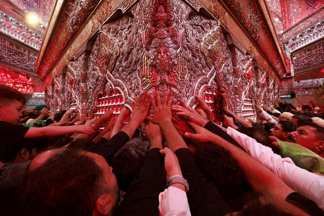 Shi'ite Muslim pilgrims reach out to touch the tomb of Imam Hussein located inside the Imam Hussein shrine ahead of Ashura, the holiest day on the Shi'ite Muslim calendar, in the holy city of Kerbala, Iraq on July 15, 2024. (Photo by Ahmed Saad/Reuters)