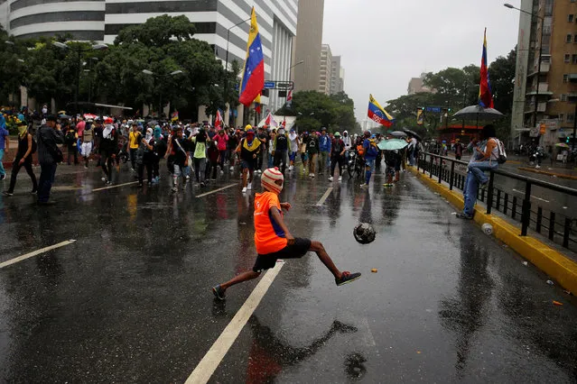 A hooded boy plays with a ball as demonstrators march while rallying against Venezuela's President Nicolas Maduro's government in Caracas, Venezuela June 29, 2017. (Photo by Ivan Alvarado/Reuters)
