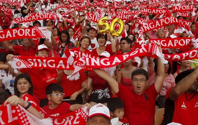 People hold up Singapore banners during Singapore's Golden Jubilee celebration parade at Padang near the central business district August 9, 2015. (Photo by Edgar Su/Reuters)