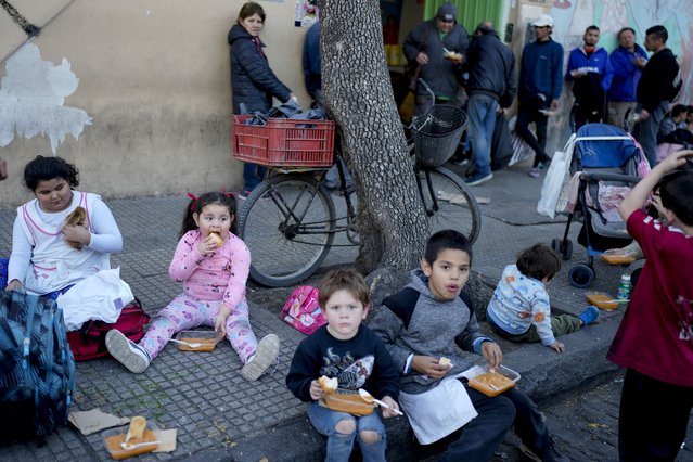 Children eat a free, cooked meal outside a soup kitchen on the outskirts of Buenos Aires, Argentina, September 12, 2024. (Photo by Natacha Pisarenko/AP Photo)