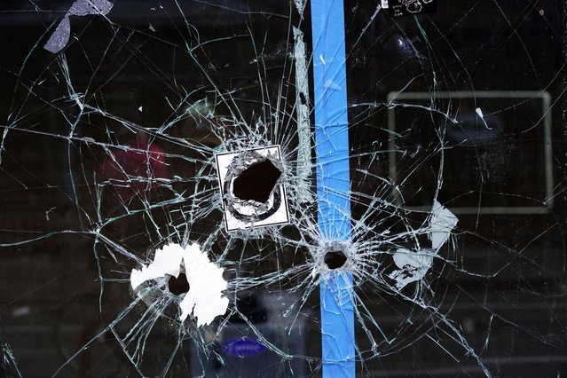 A storefront window with bullet holes is seen at the scene of a fatal overnight shooting on South Street in Philadelphia, Sunday, June 5, 2022. (Photo by Michael Perez/AP Photo)