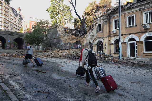 Local residents with suitcases walk past buildings damaged as a result of a missile strike in Odesa on July 23, 2023, amid the Russian invasion of Ukraine. Ukraine on Sunday said 19 people, including four children, were wounded in a Russian overnight missile attack on Odesa that also killed one person. (Photo by Oleksandr Gimanov/AFP Photo)