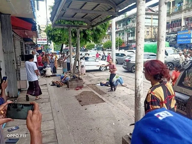 In this photo provided by the information office of Myanmar's military, four injured people can be seen lying on the pavement after an explosion at a bus stop in downtown Yangon on May 31, 2022. One person was killed and nine wounded when what authorities described as a handmade bomb exploded. The military and its foes blamed each other for the blast. (Photo by Myanmar Military True News Information Team via AP Photo)